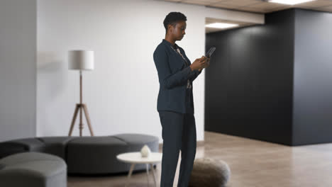 Businesswoman-In-Suit-Messaging-On-Mobile-Phone-In-Modern-Open-Plan-Office